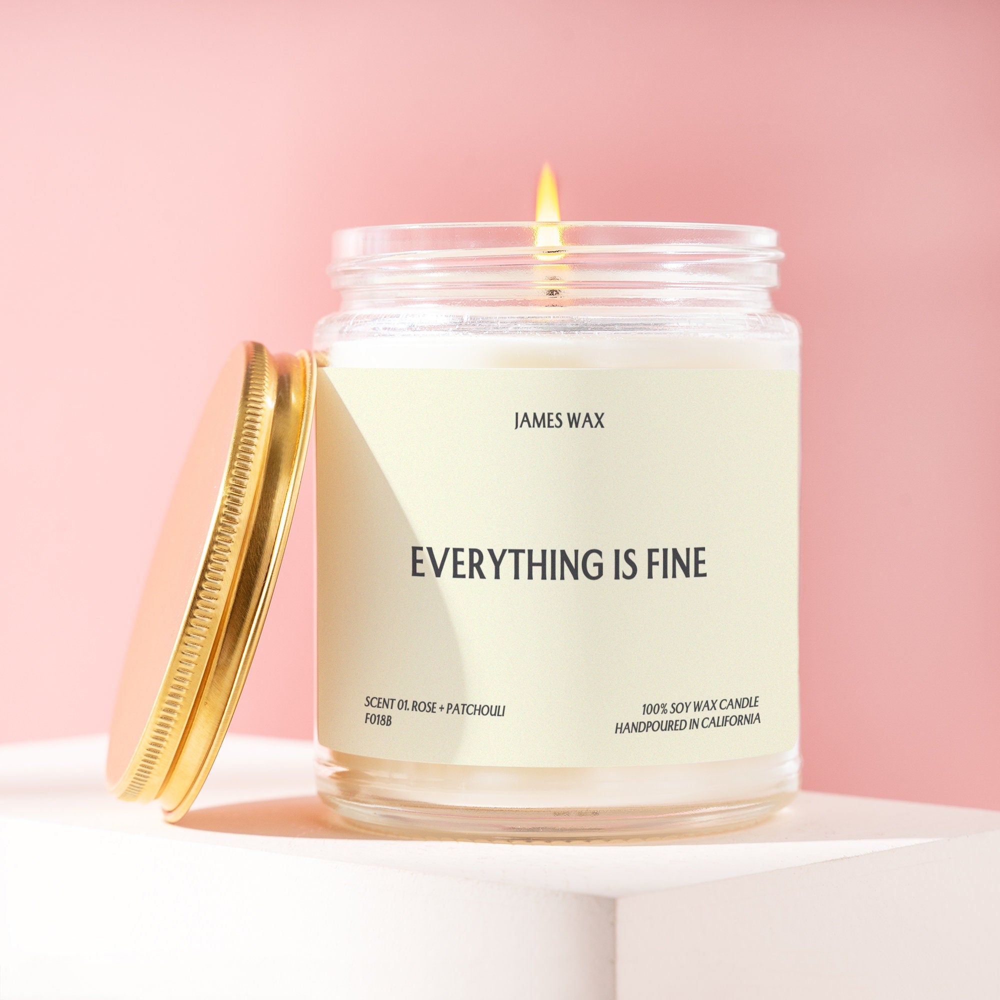 a white candle with a gold lid sitting on top of a table